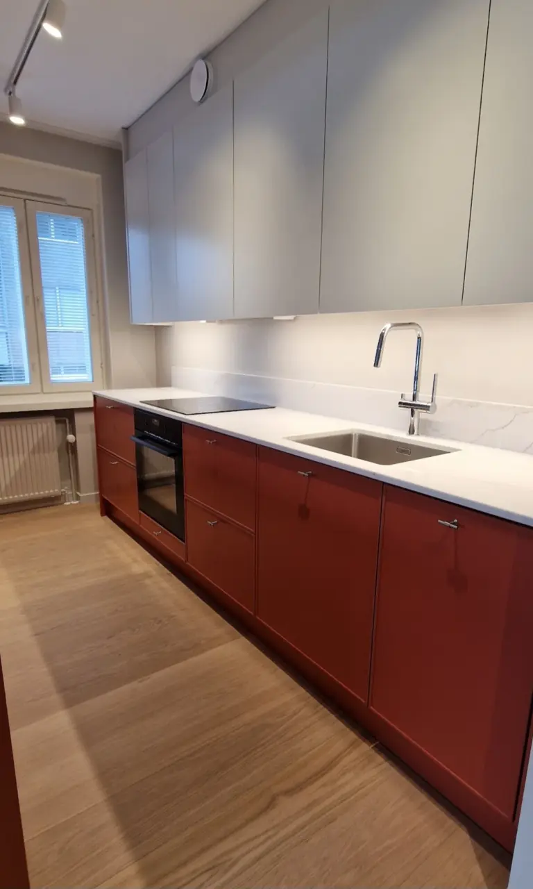 Keittiö, jossa punaruskeat alakaapit, valkoinen työtaso ja harmaat yläkaapit